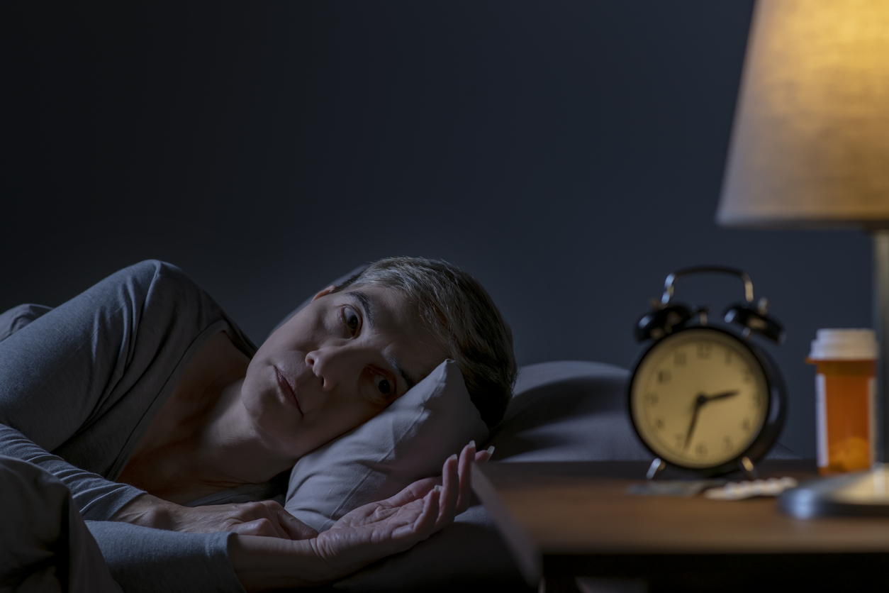 Depressed senior woman lying in bed cannot sleep from insomnia
