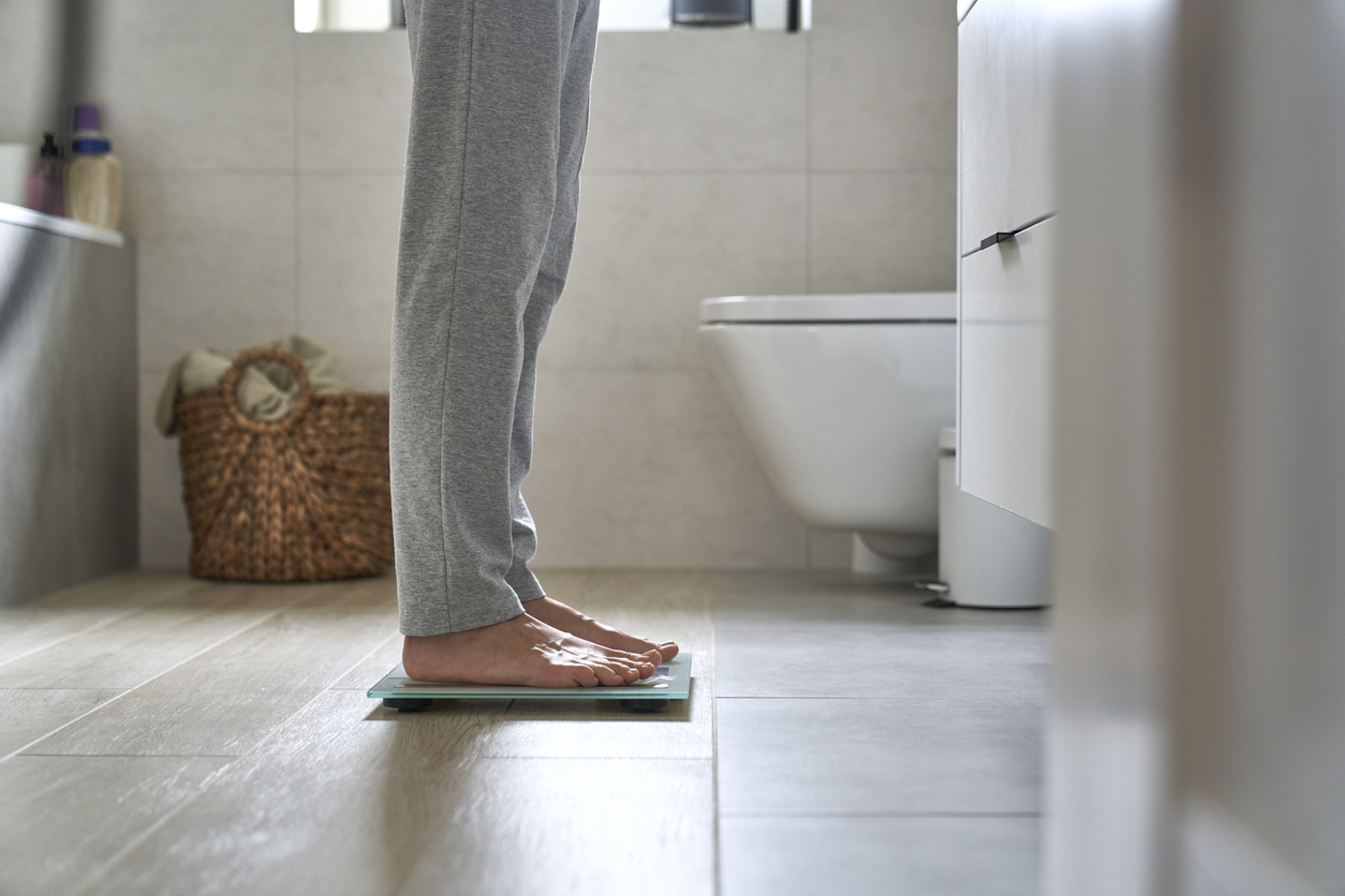 Closeup of the legs of a women with an eating disorder wearing sweatpants and standing on a scale