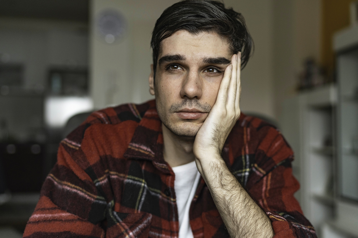 Man with depression sitting with his hand supporting his head with a sad look