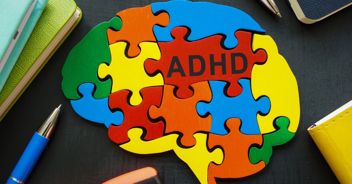 A brain made of red, yellow, orange, blue, and green puzzle pieces has an inscription with the letters “ADHD.”