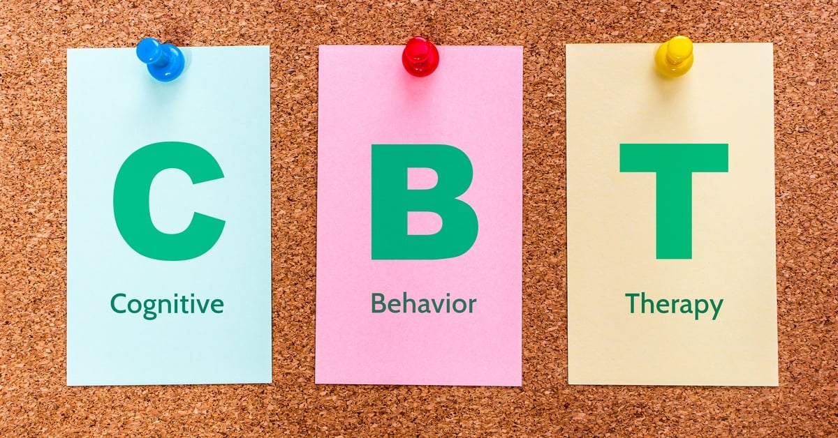 Three colorful notes — blue, pink, and yellow — pinned to a corkboard display CBT, standing for Cognitive Behavior Therapy.