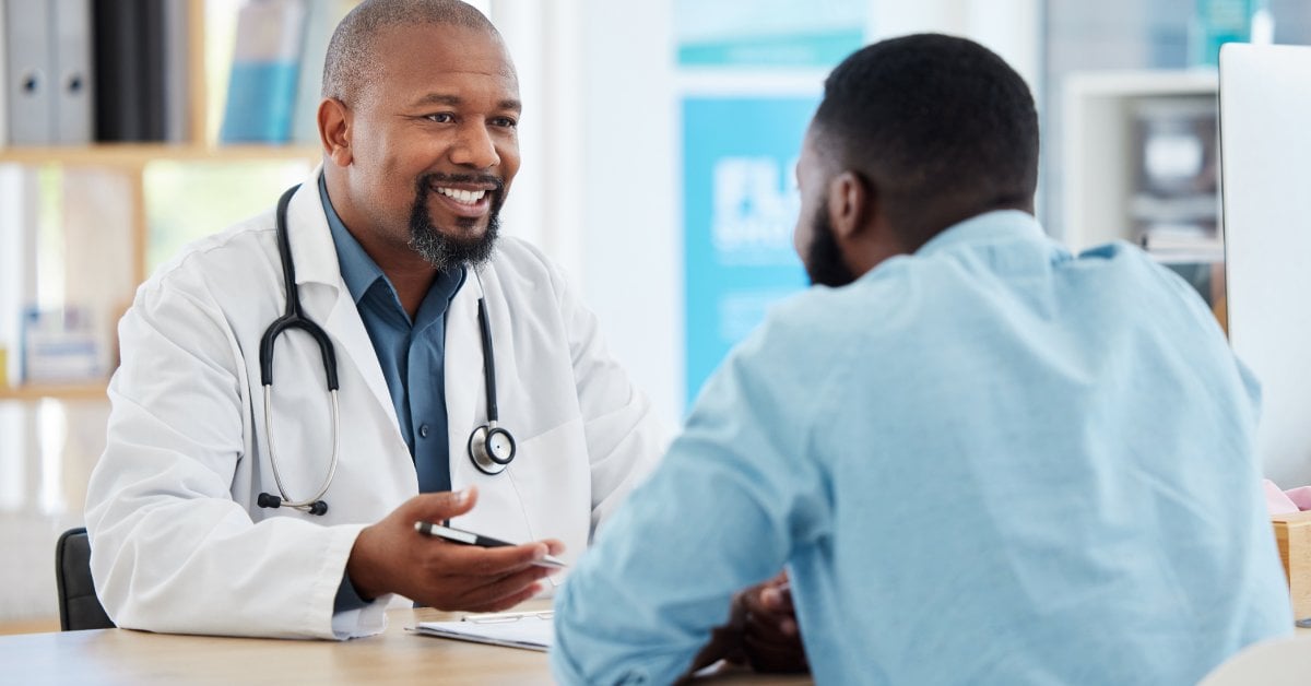 A smiling doctor speaks with a patient during a consultation, creating a friendly, supportive atmosphere in a medical office.