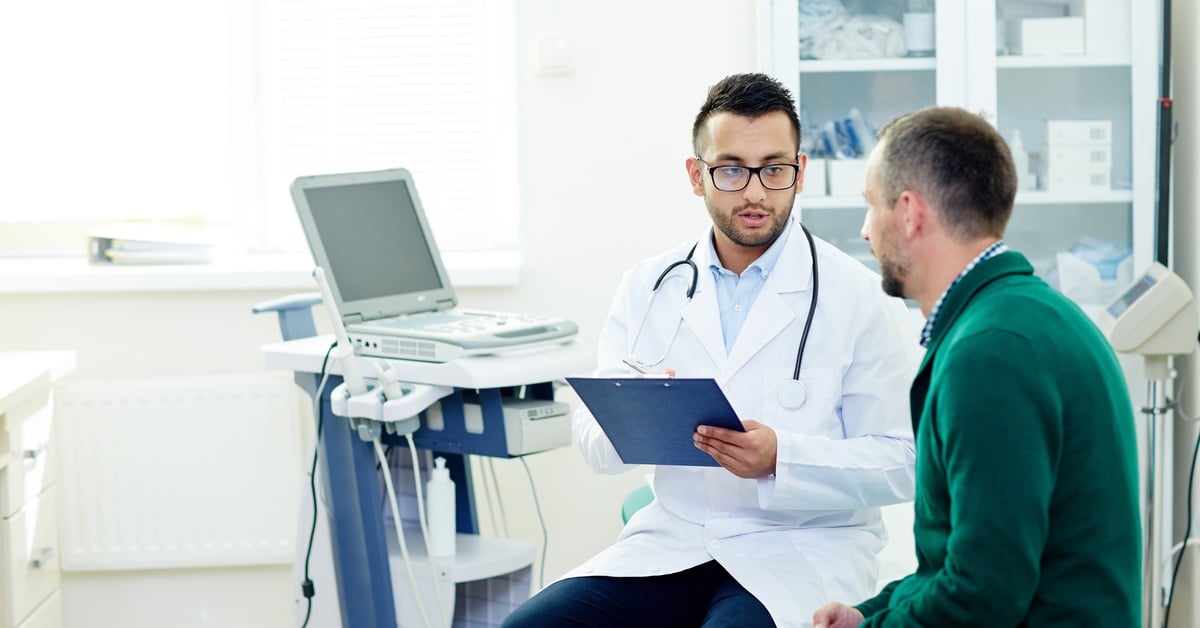 A doctor reviews paperwork with a patient during a consultation, discussing symptoms and medical diagnosis.