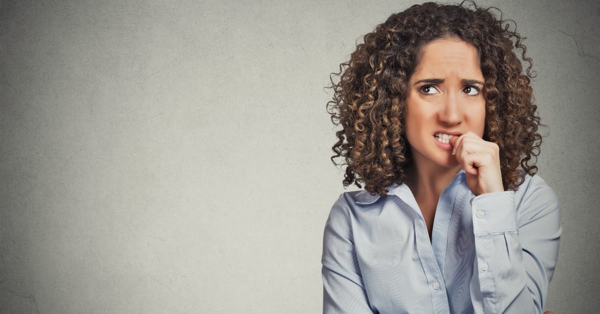 A woman bites her nails anxiously, appearing nervous as she anticipates her first psychiatry appointment.