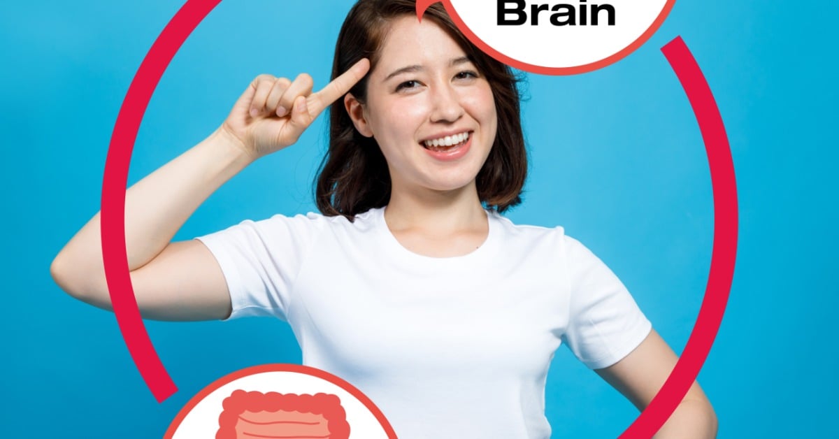 A woman points to her head and gut to illustrate the gut-brain connection and how the two systems communicate.