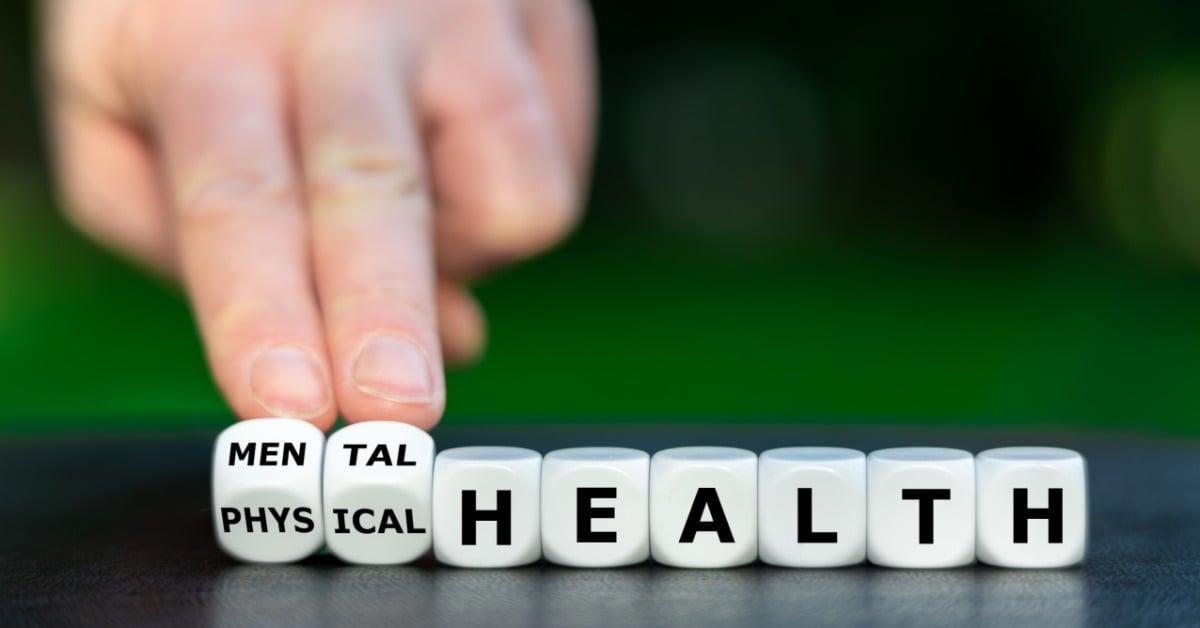 A hand turns the dice to switch the word from physical health to mental health, illustrating the connection between both.