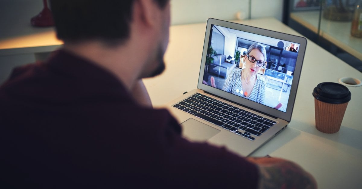 A man attends a telehealth video session on his laptop, speaking with a mental health provider from home.