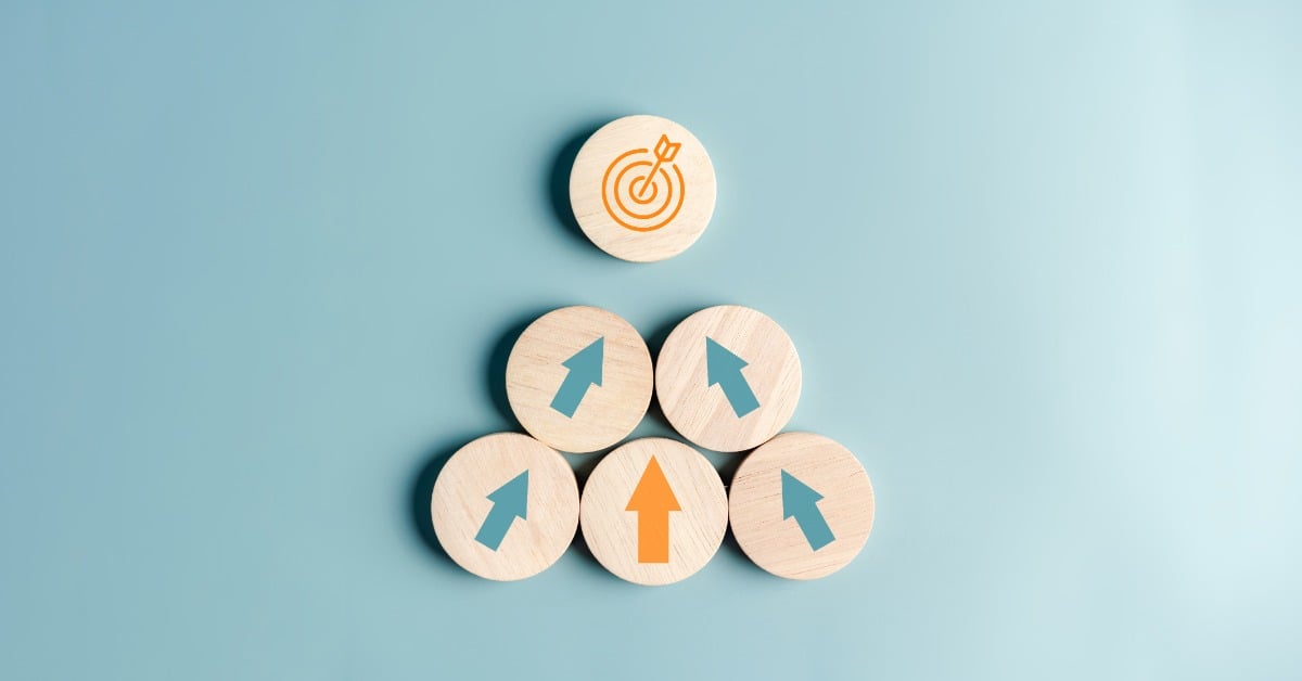 Wooden discs are arranged in a pyramid. Five are marked with upward arrows, while the top piece has a target symbol.