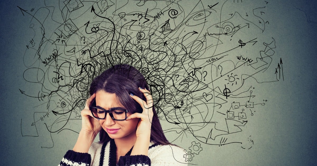 A woman with closed eyes presses her hands to the sides of her head. Drawn lines and symbols radiate from her head.